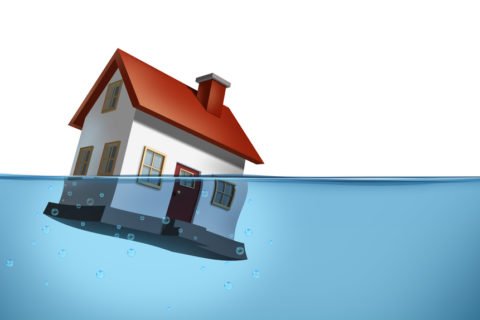 Sinking home and housing crisis with a house in the water on a white background showing the real estate housing concept of the challenges of home ownership and